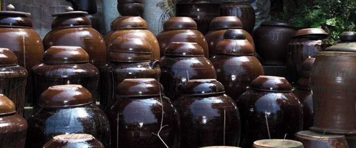 A collection of traditional pottery, including various shapes and sizes, displayed against a rustic backdrop.