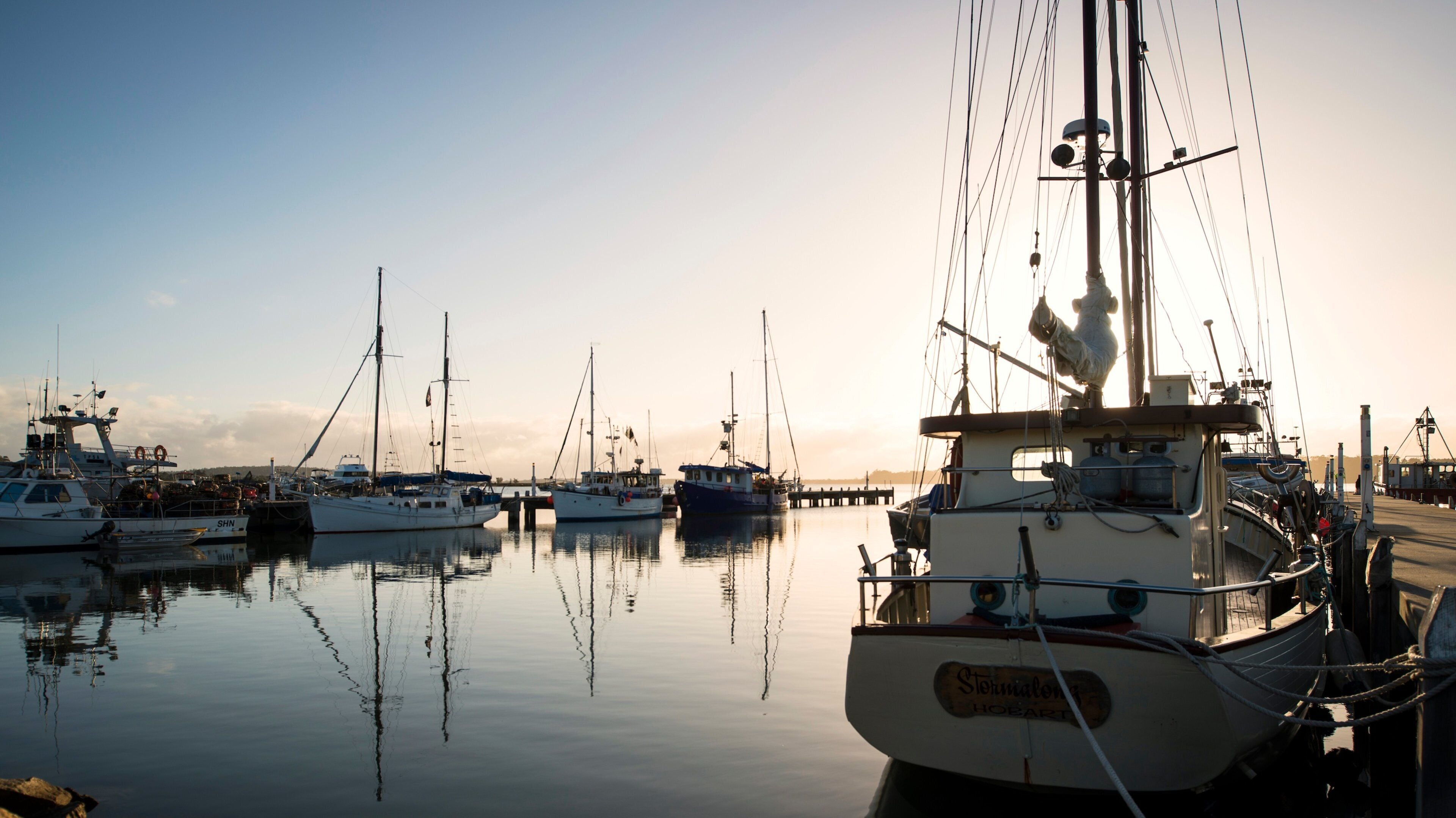 A marina with several sailboats docked at sunset.