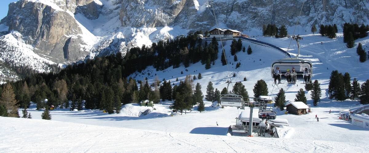 A ski lift with a mountain backdrop, snow-covered slopes, and a clear blue sky.