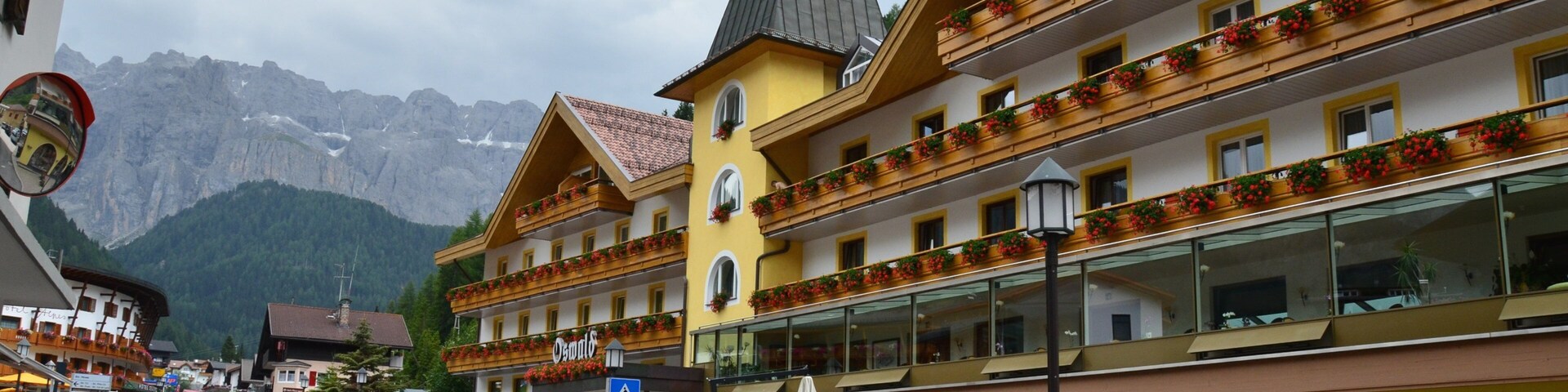 A street with buildings, cars, and mountains in the background.