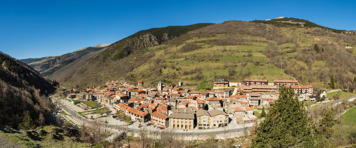 A mountainous village with terracotta-roofed buildings nestled in a valley.