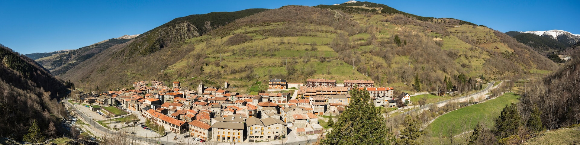 A mountainous village with terracotta-roofed buildings nestled in a valley.