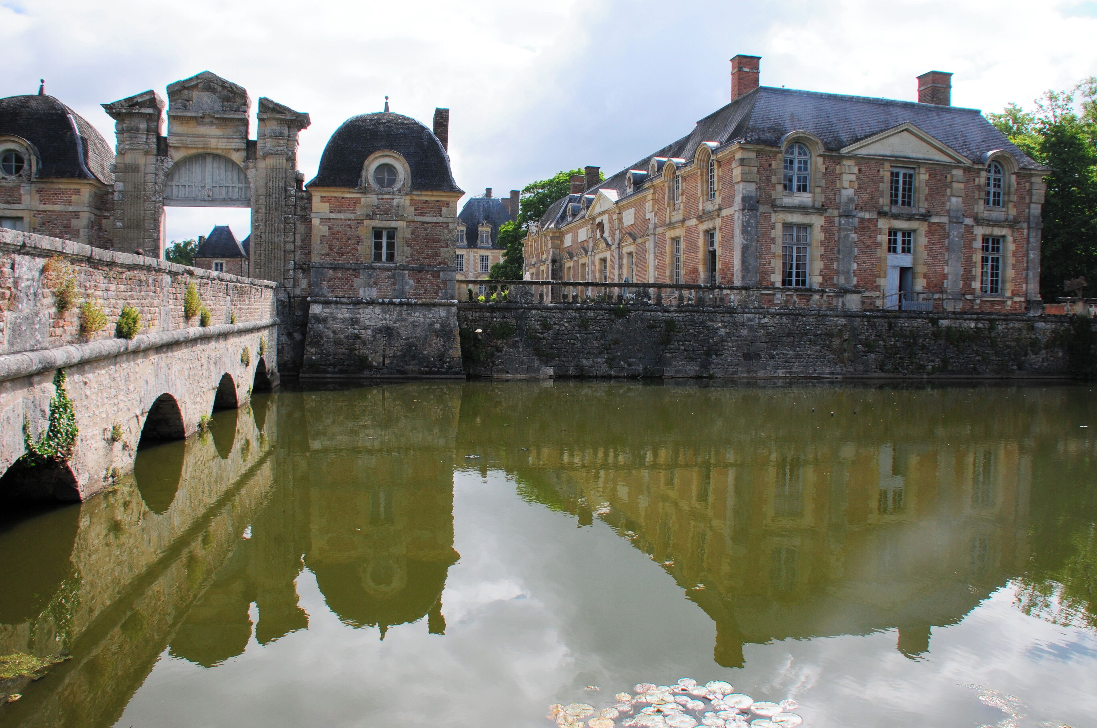 A historic stone bridge over a calm river, reflecting the surrounding buildings and sky.