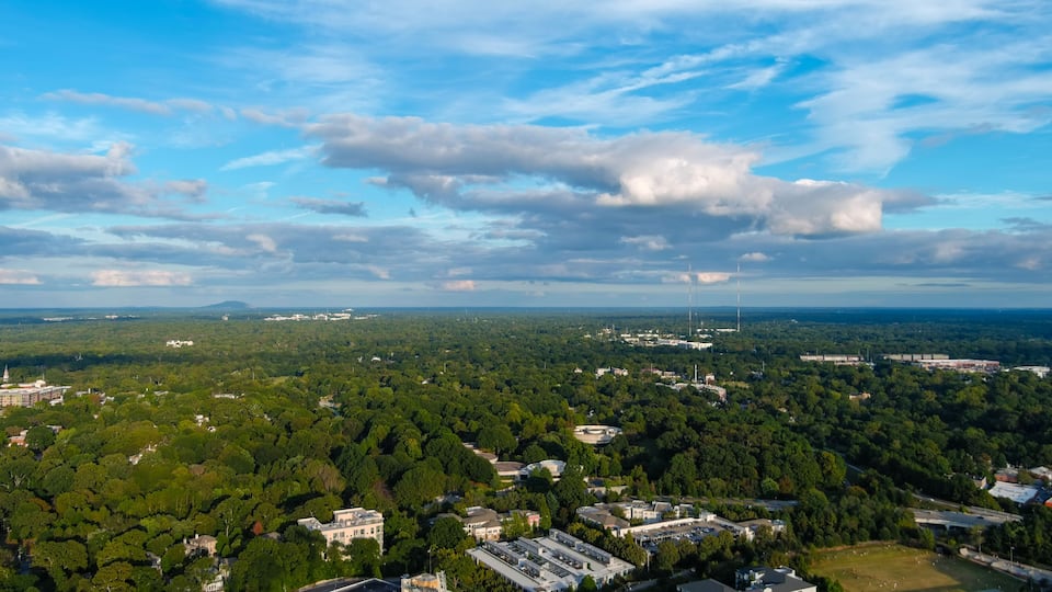 A cityscape with dense green areas, buildings, and two prominent towers.