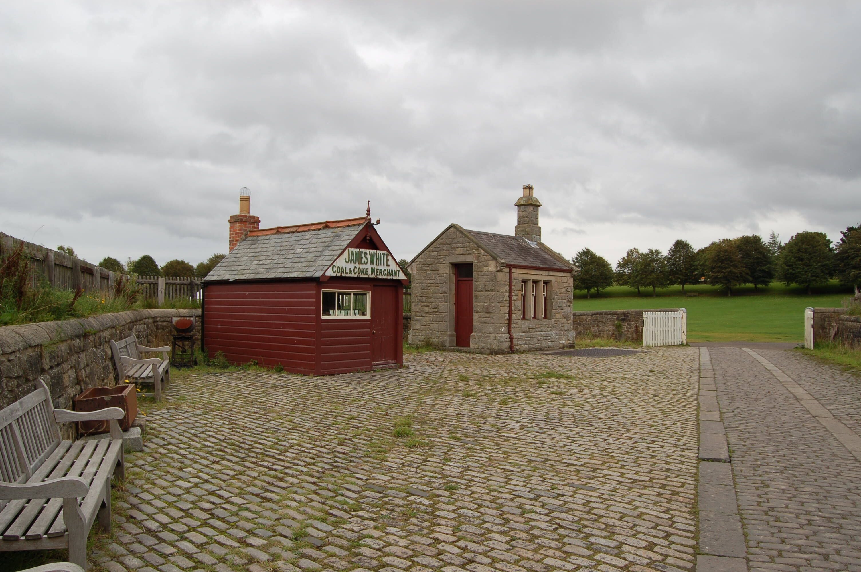 A stone building with a red door and a sign that reads "James White Coal Coke Merchant."