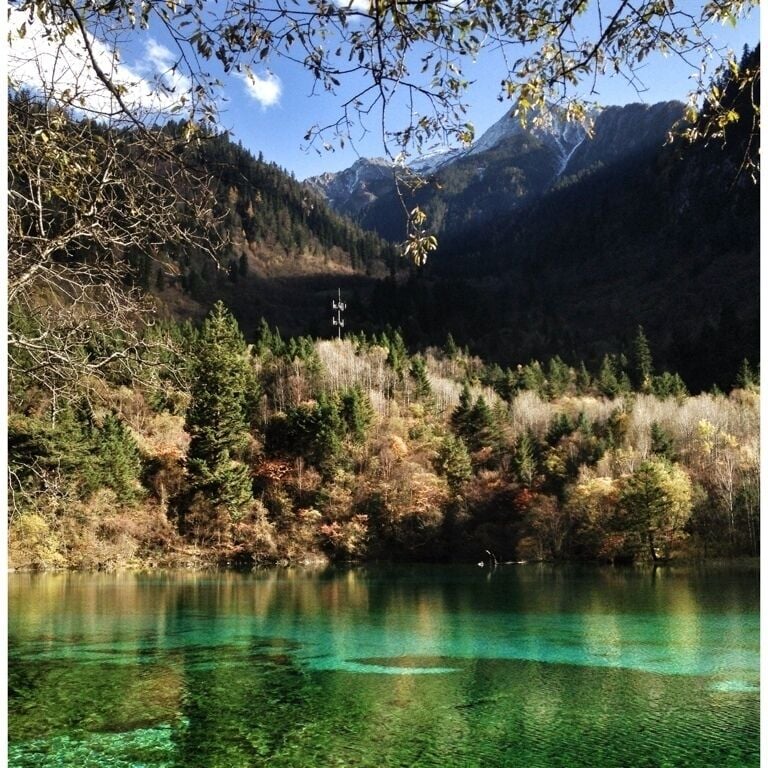 A clear mountain lake surrounded by forested hills.