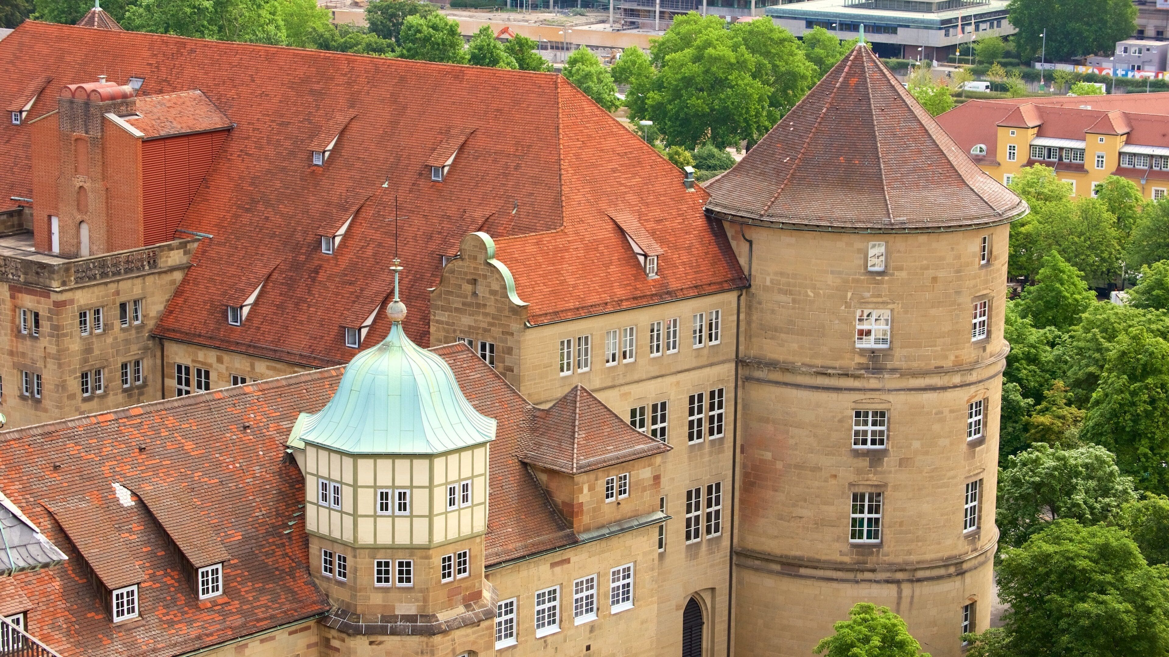 A historic building with a red-tiled roof, a green dome, and a tall tower.