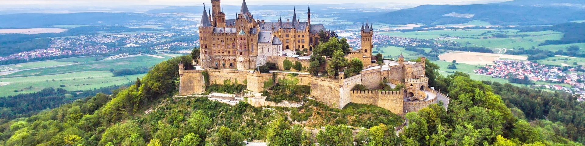A castle on a hill surrounded by dense forest.