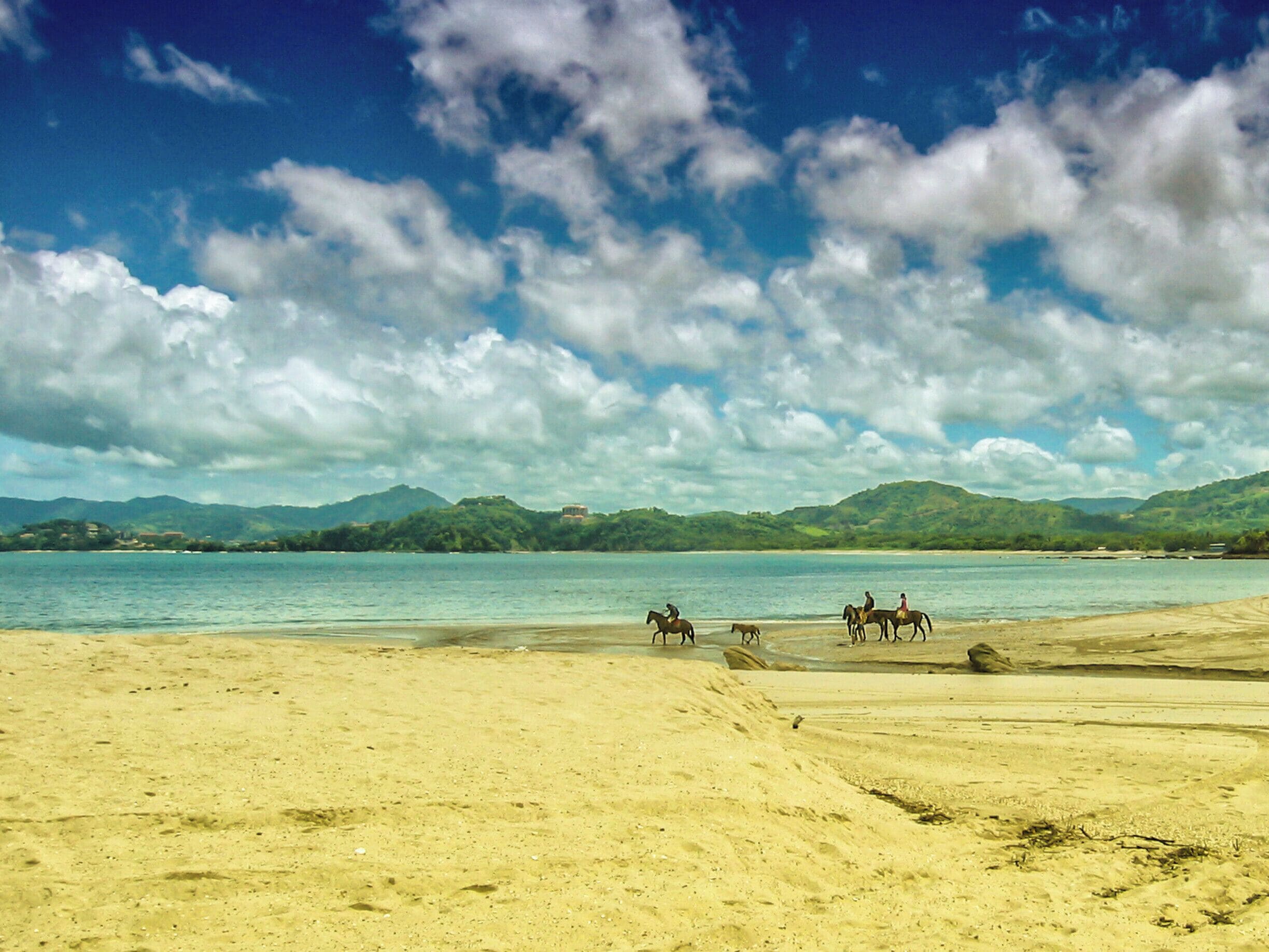 Horseback riders on the beach on Playa Hermosa in the Guanacaste region of Costa Rica. Hermosa means "beautiful" in Spanish, which makes it a perfect name for this gorgeous beach with calm surf and mountain views. #costarica #beach #playahermosa #guanacaste