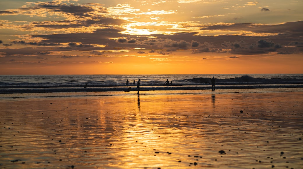 A beach with people at sunset.