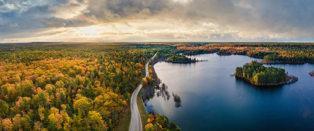 A winding road through a forested area with a lake and islands.