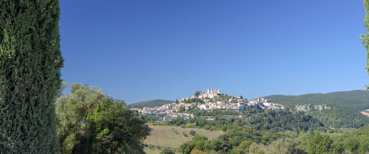 A town on a hill surrounded by trees and hills.