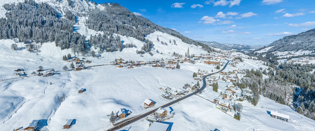 A snow-covered mountain village with houses, a church, and a winding road.