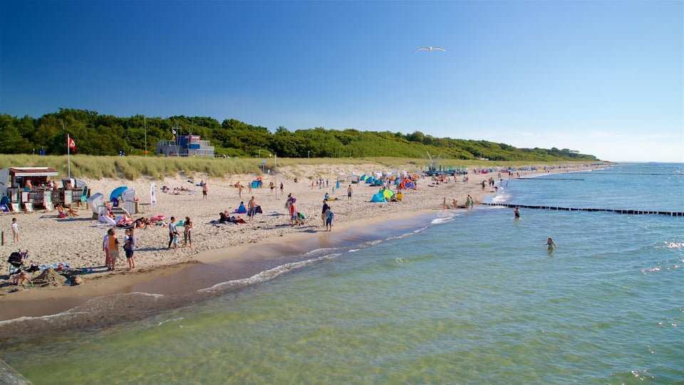 A crowded beach with people sunbathing and swimming, tents, and a lifeguard tower.