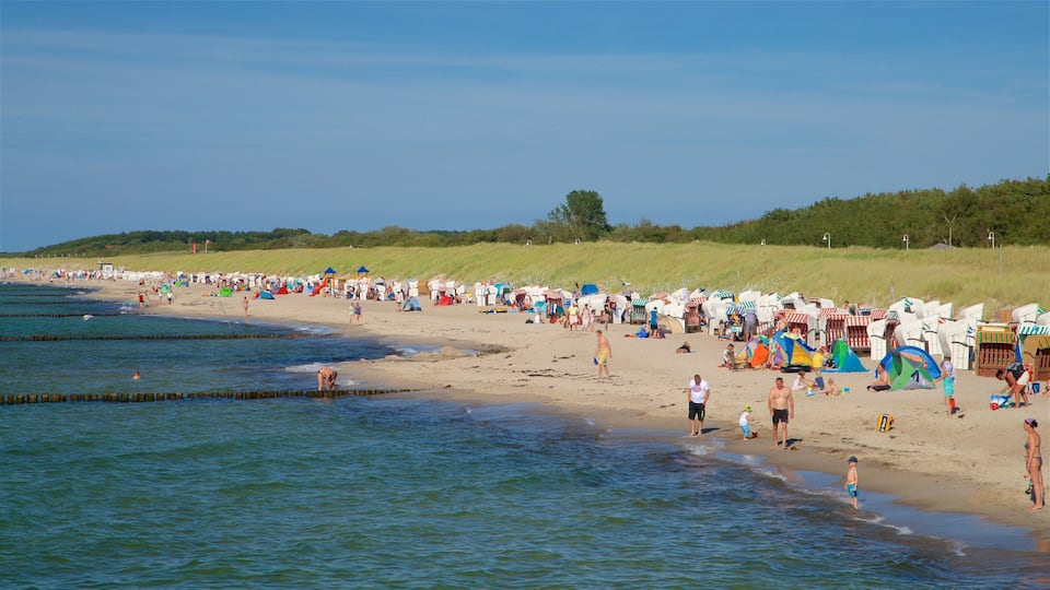 A crowded beach with people, tents, and beach chairs.