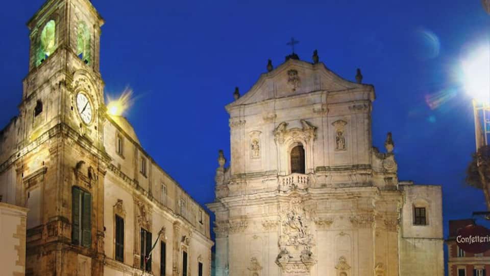 A historic church with a clock tower and a statue in front.