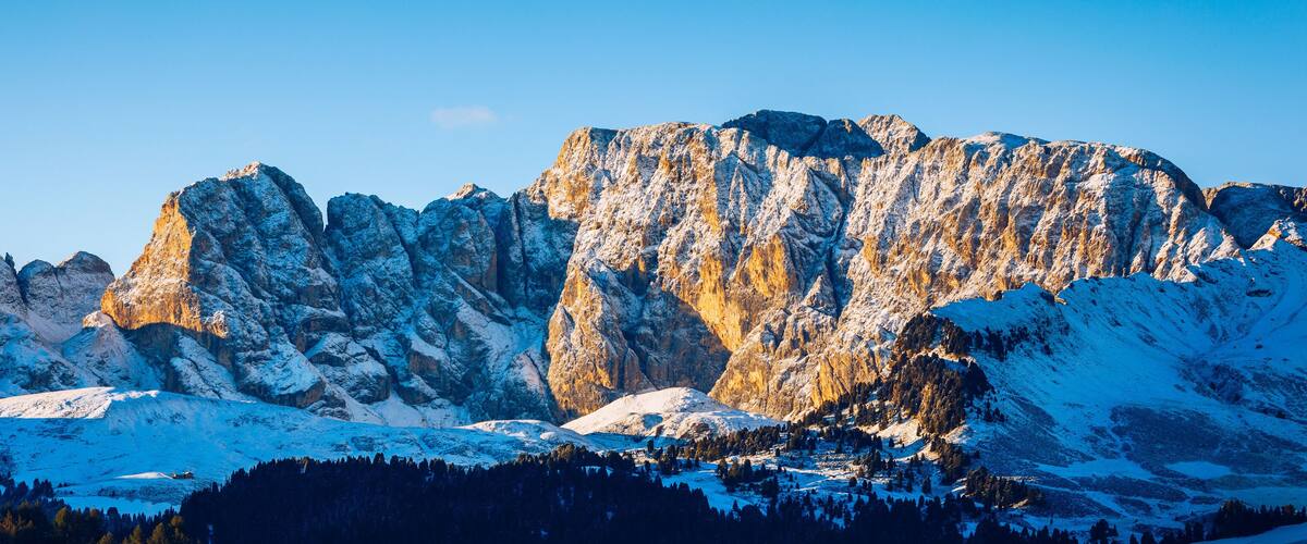 A snow-covered mountain range with rugged peaks and a clear sky.