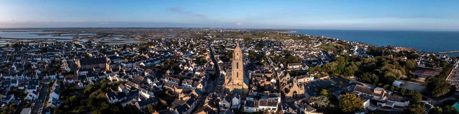 A coastal town with a prominent church, dense residential area, and a view of the sea.