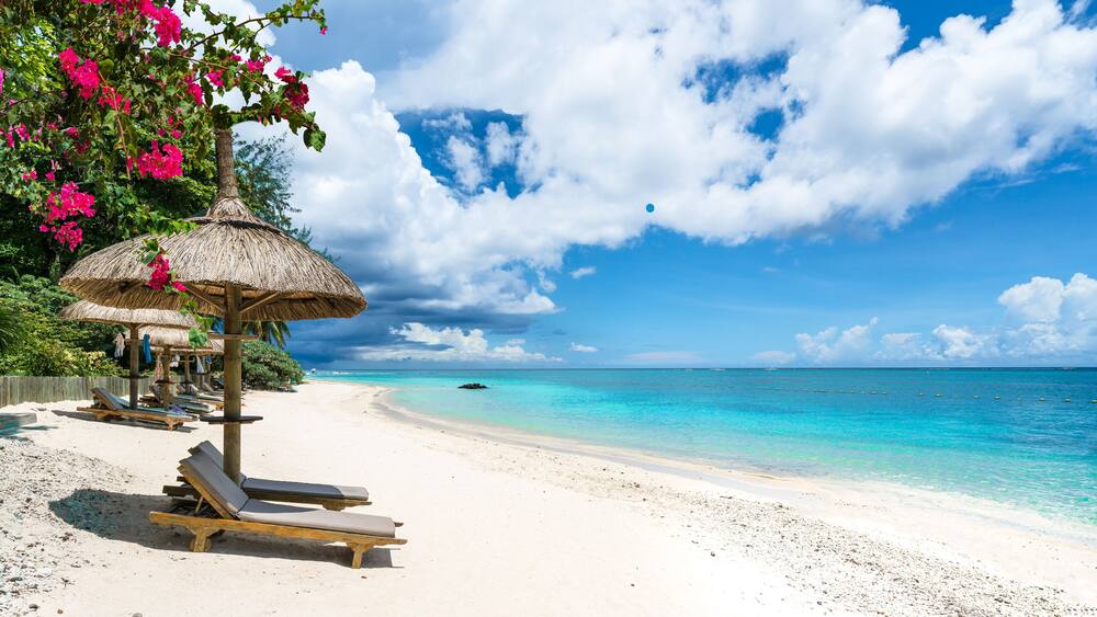 Public beach with lounge chairs and umbrellas in Pointe aux Canonniers, Mauritius island, Africa