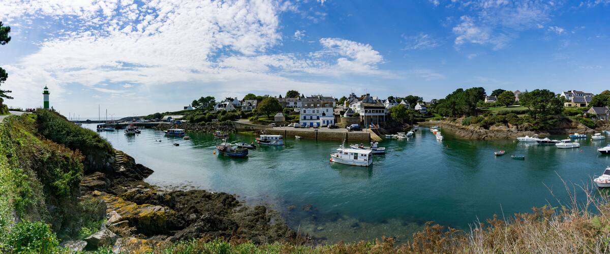A coastal town with a lighthouse, boats, and houses along the shoreline.