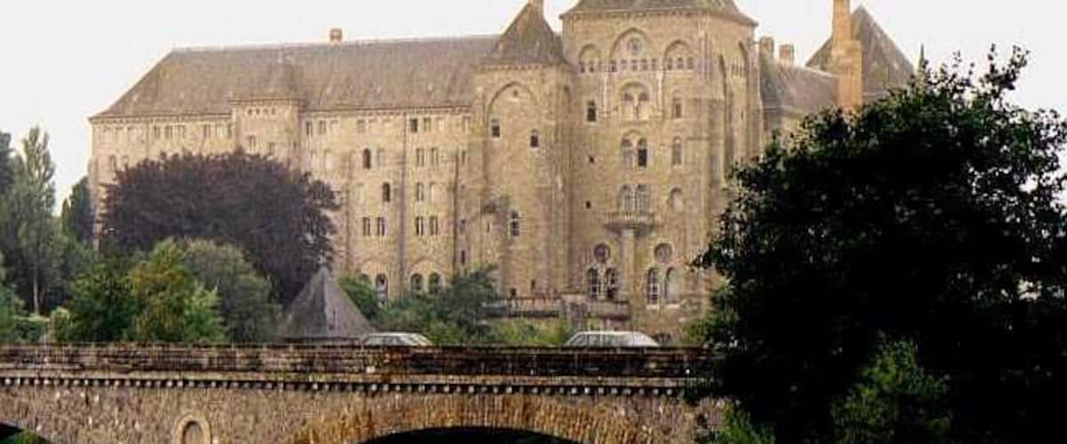 A large historic building with a bridge in the foreground.