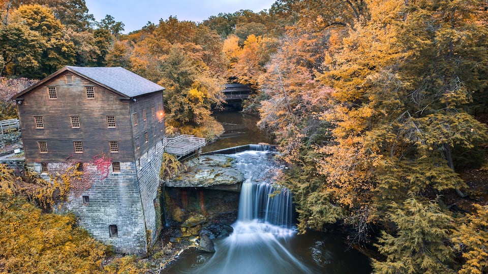 A historic stone building, a waterfall, and autumn foliage.