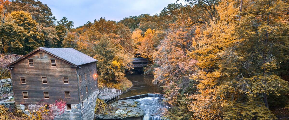 A historic stone building, a waterfall, and autumn foliage.