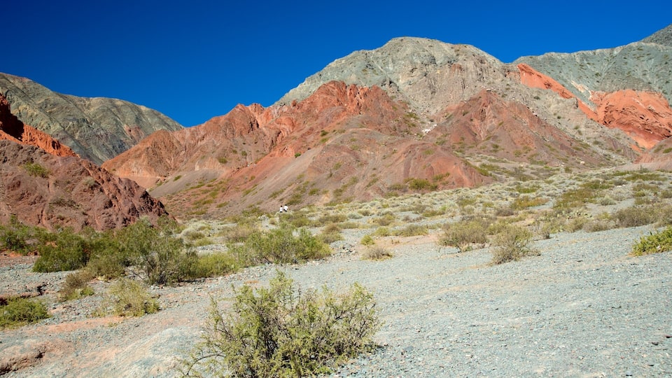 A rugged mountain landscape with reddish-brown rock formations and sparse vegetation.