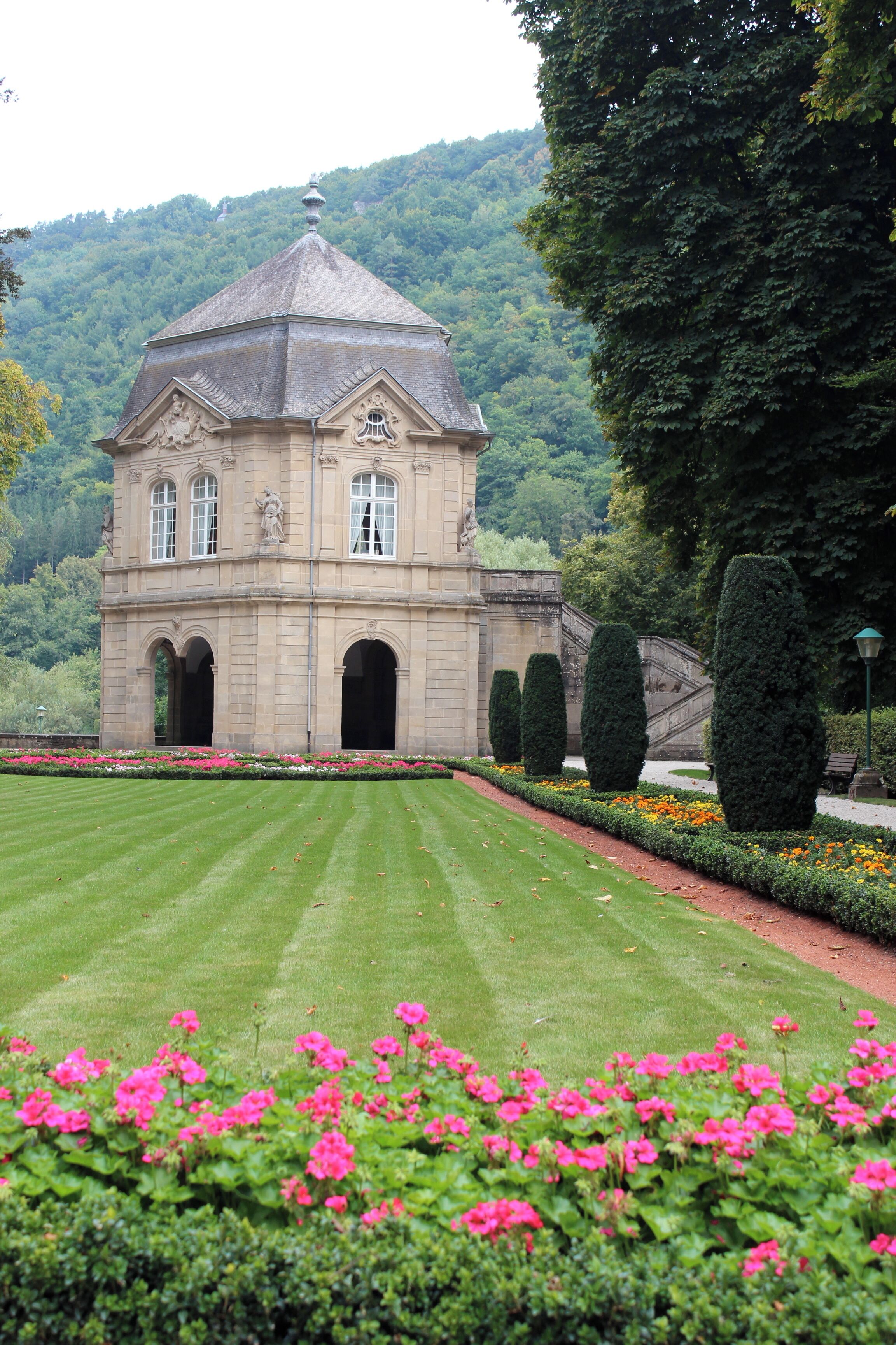 A historic building with a dome, surrounded by a well-manicured lawn and vibrant flowers.