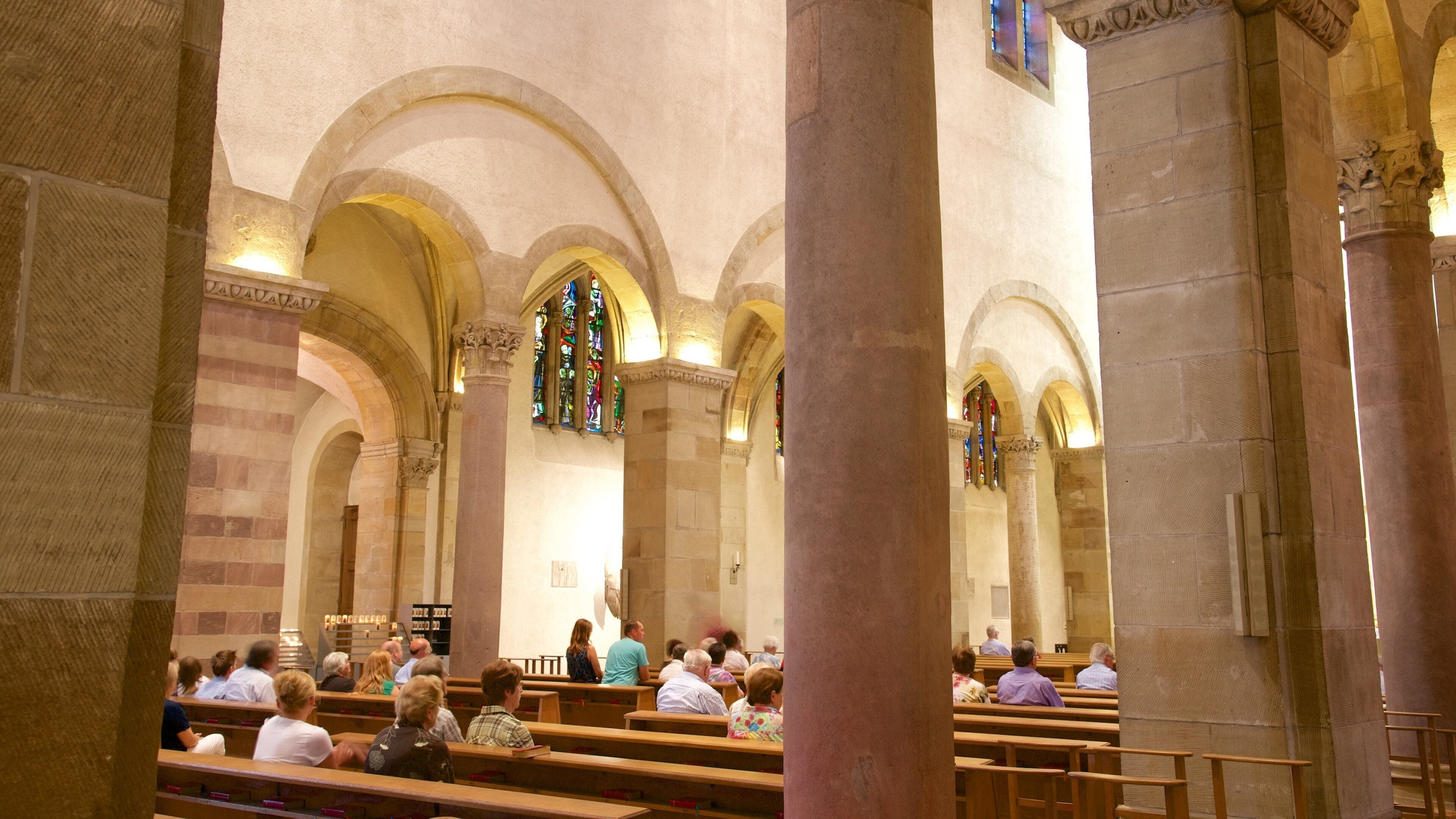 A church interior with arched ceilings, stained glass windows, and pews.