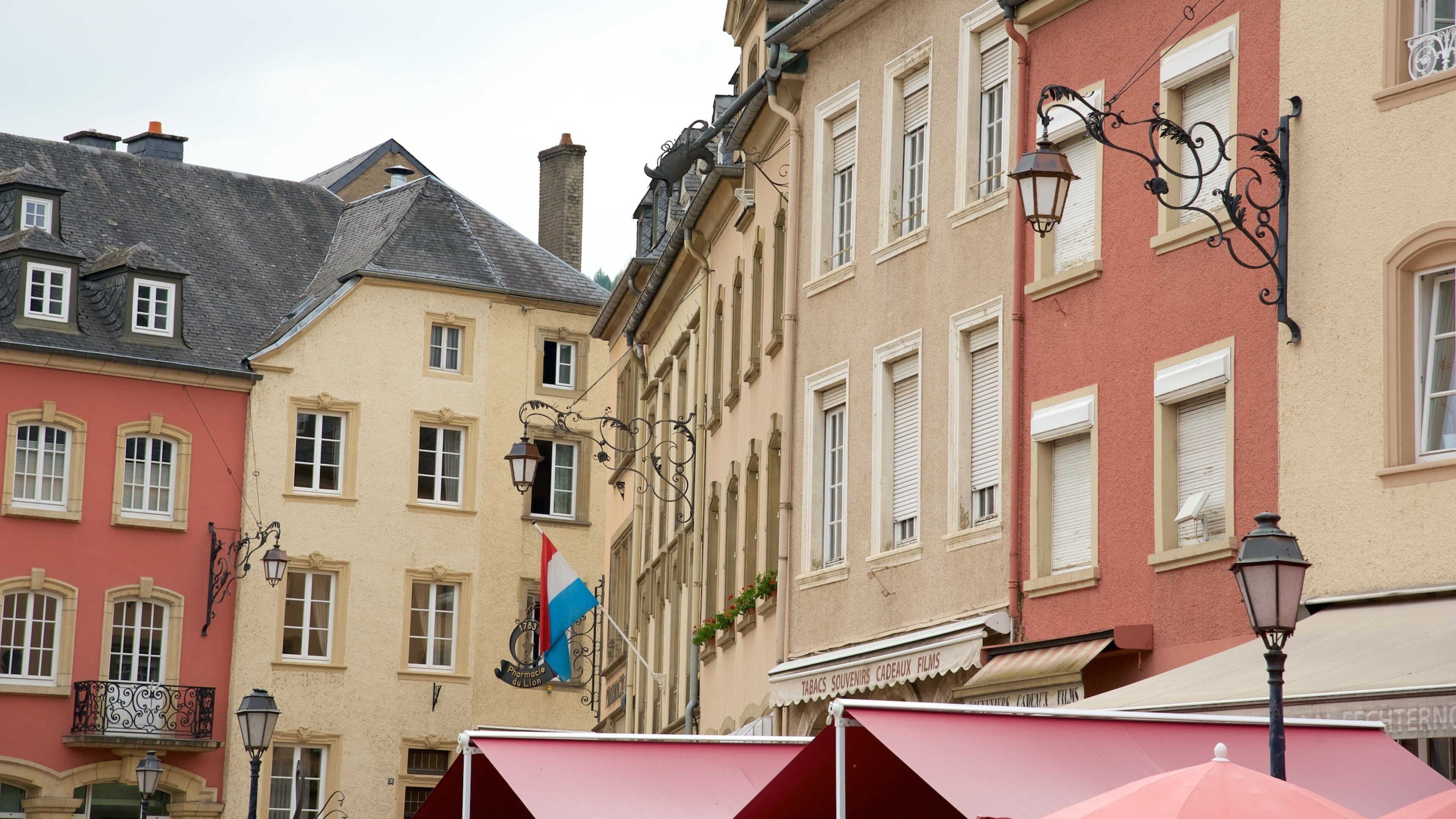 A street with colorful buildings, a pharmacy, and a café.