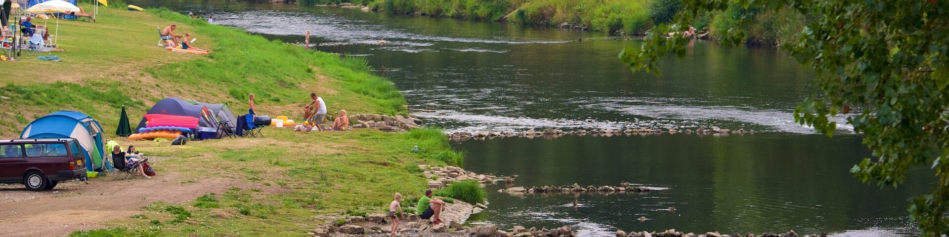 Un río con gente y tiendas de campaña a orillas.