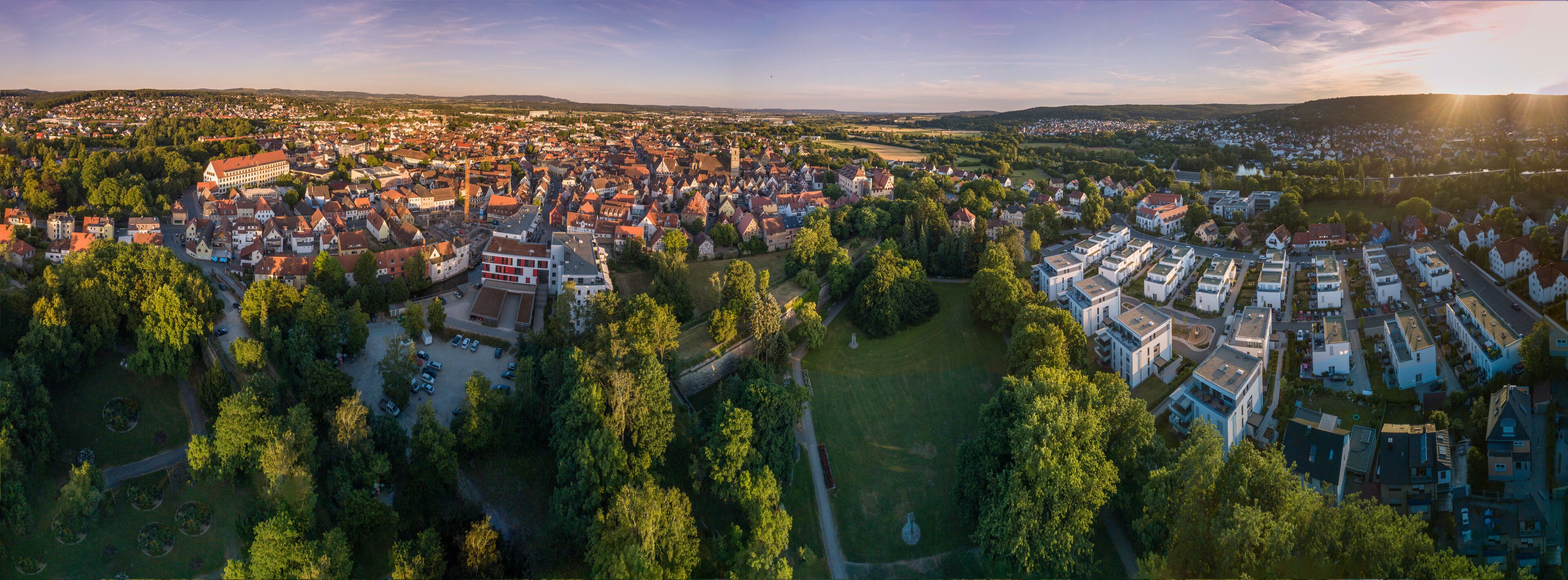 An aerial view of a town with historic buildings, a river, and surrounding greenery.