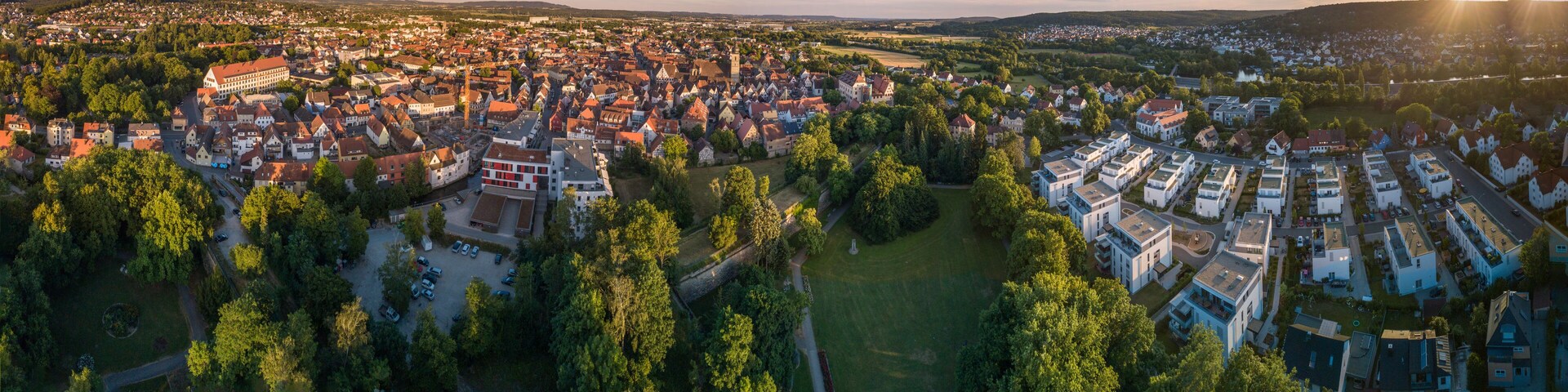 An aerial view of a town with historic buildings, a river, and surrounding greenery.