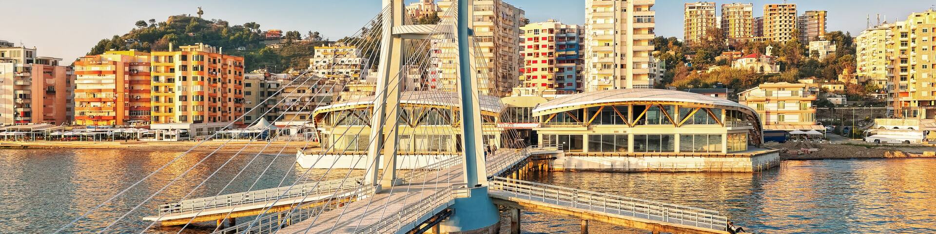 A modern bridge over a river with a cityscape in the background.