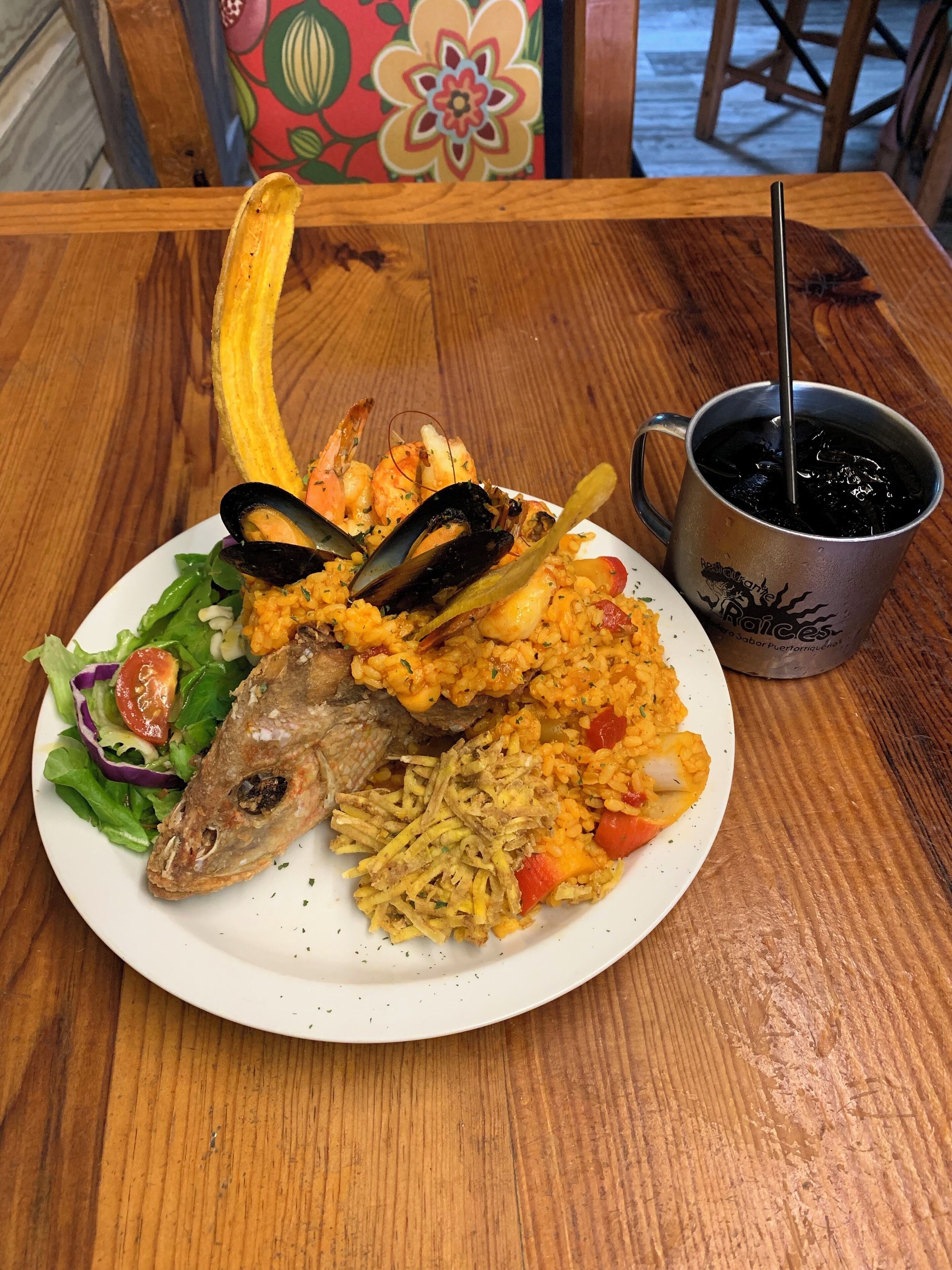 A plate of seafood, including mussels and shrimp, with a side of rice and vegetables.