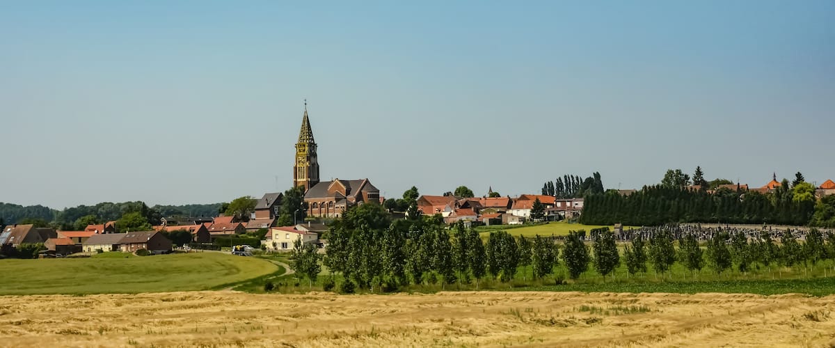 A town with a prominent church tower, surrounded by residential buildings and green fields.