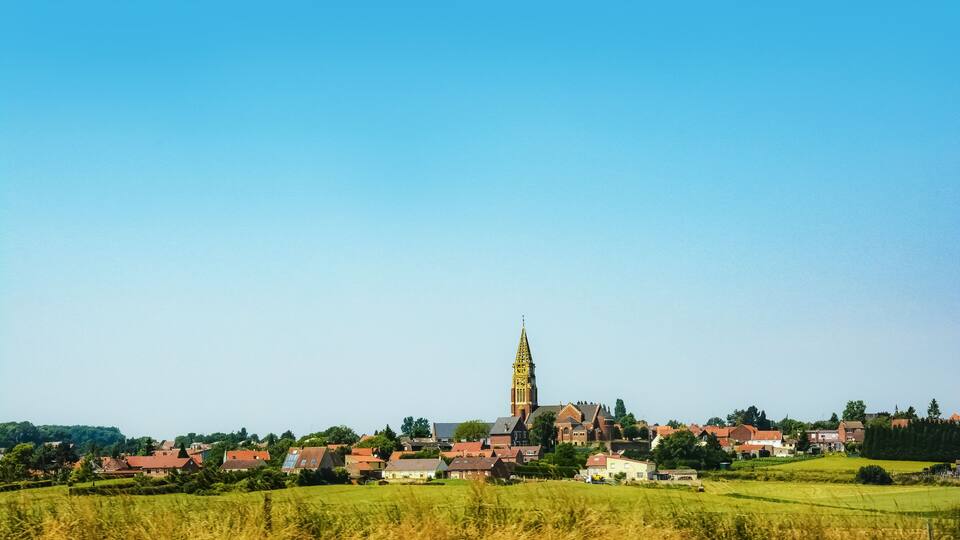 A town with a prominent church tower, surrounded by houses and fields.