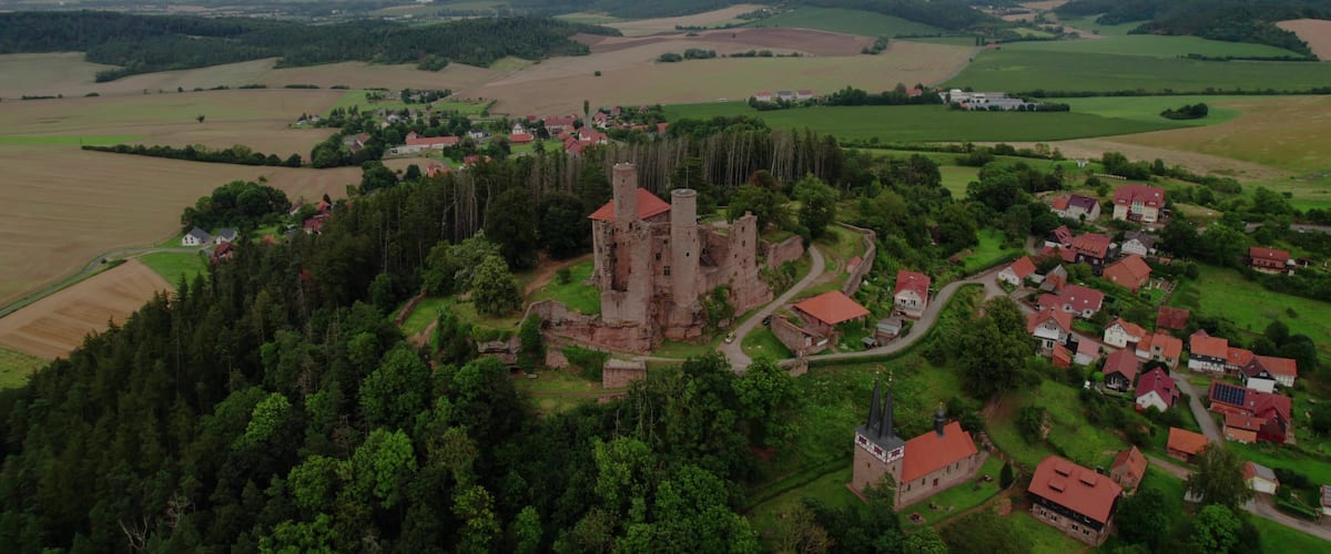 A medieval castle surrounded by a village and fields.