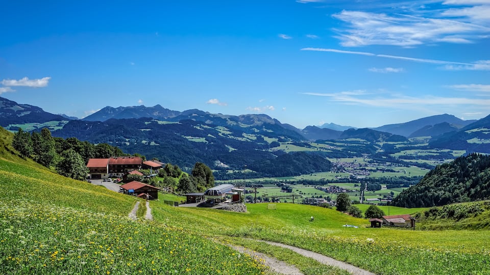 A mountainous landscape with a village, green fields, and a clear sky.