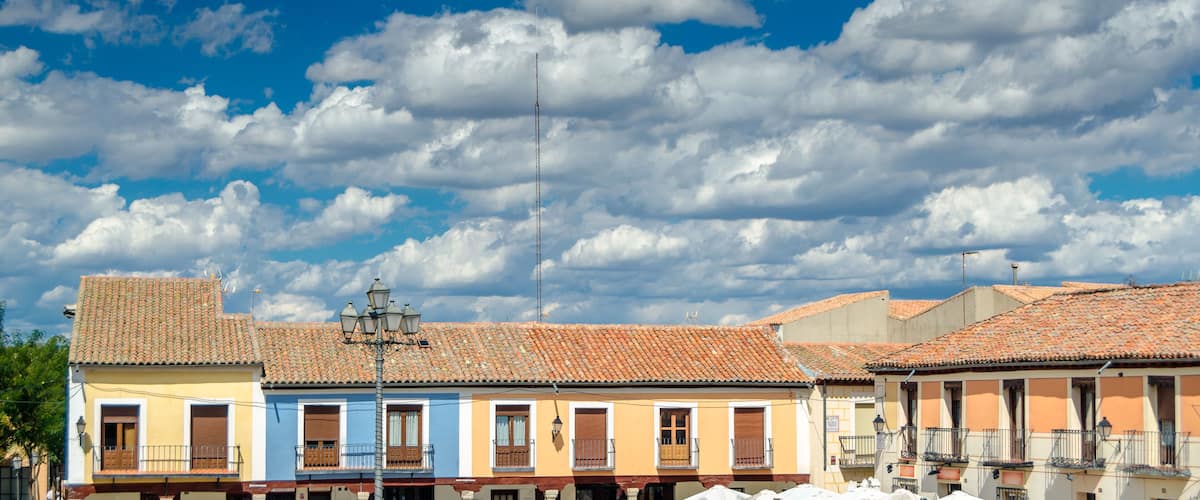 A row of colorful buildings with red-tiled roofs under a partly cloudy sky.