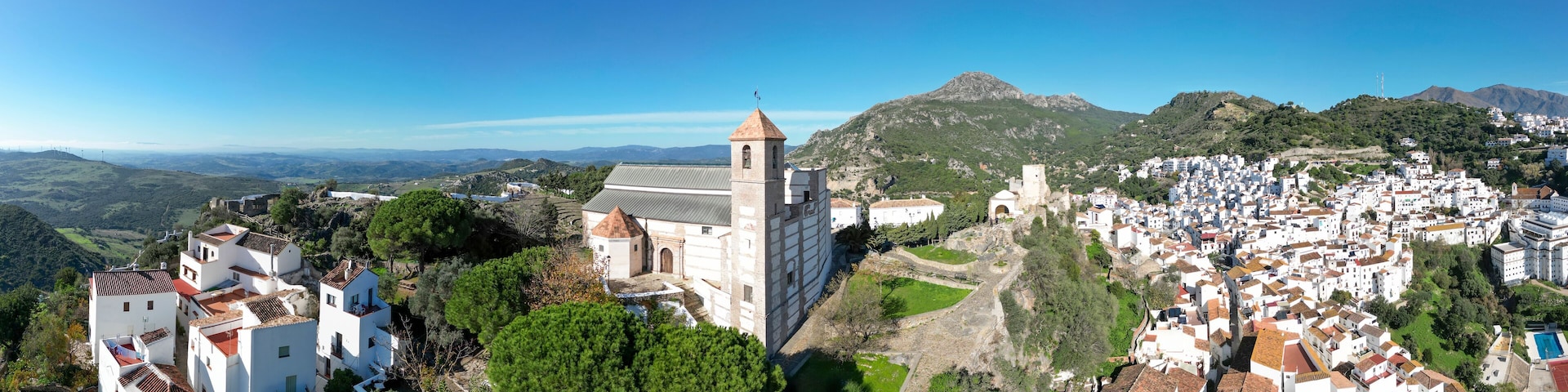 A town with white buildings, a church, and surrounding hills.