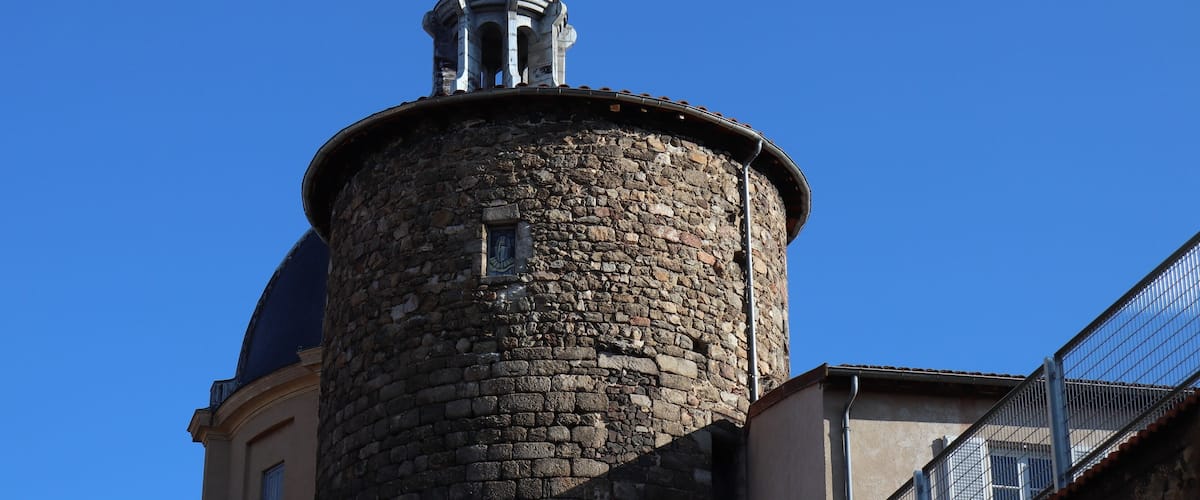 A stone tower with a dome and a spire against a clear blue sky.