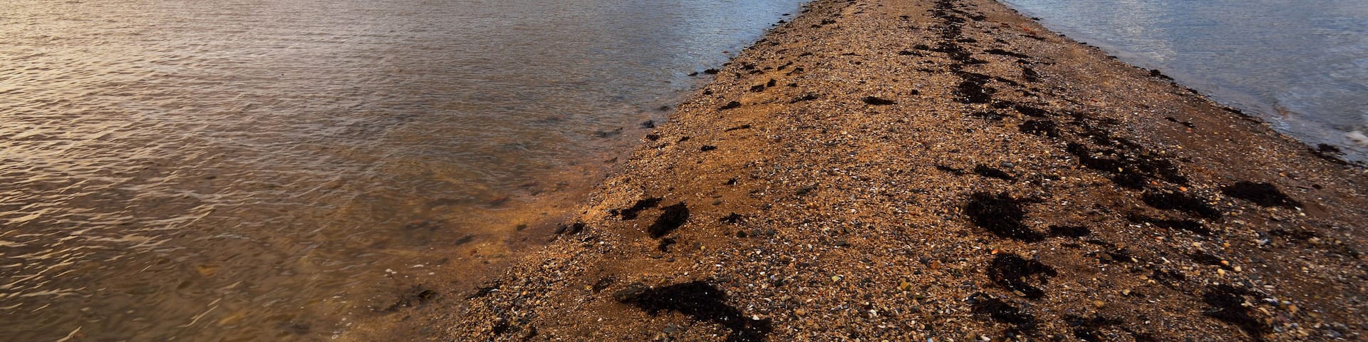 Rocky lake shores under the colorful evening sky after the rain. Dramatic cloudscape. Gare Loch, Rhu, Scotland, UK