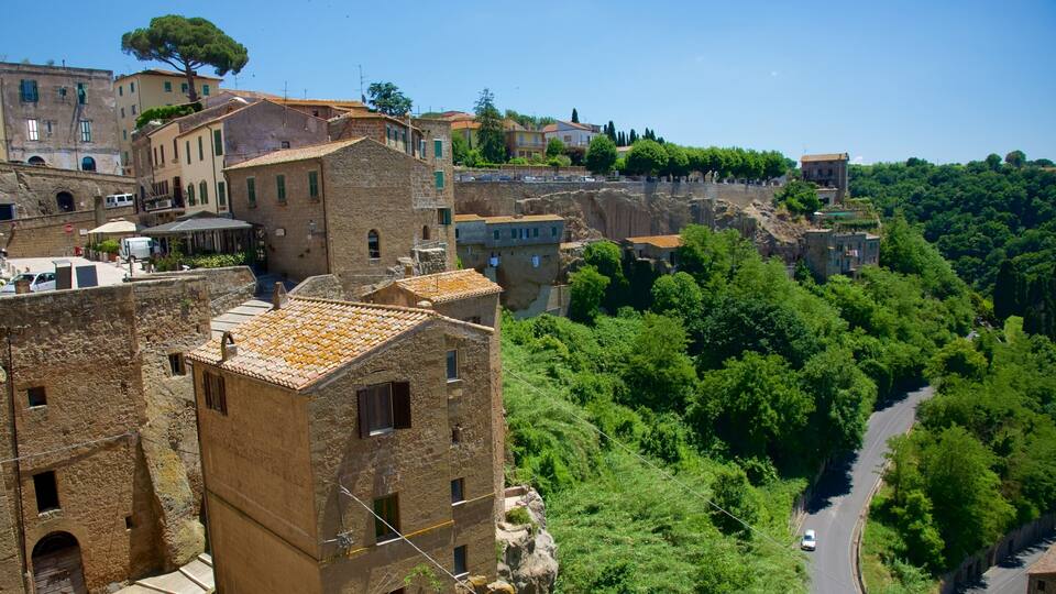 A historic town with terracotta-roofed buildings, a winding road, and lush greenery.