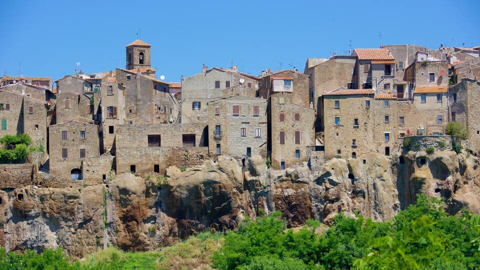 A historic town with stone buildings, a bell tower, and rocky cliffs.
