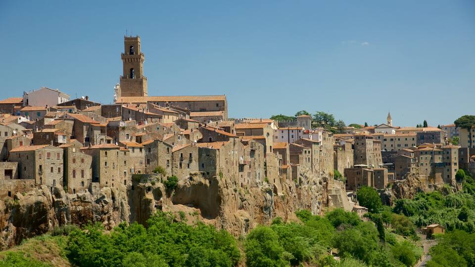 A historic town with terracotta-roofed buildings, a prominent church tower, and rugged cliffs.