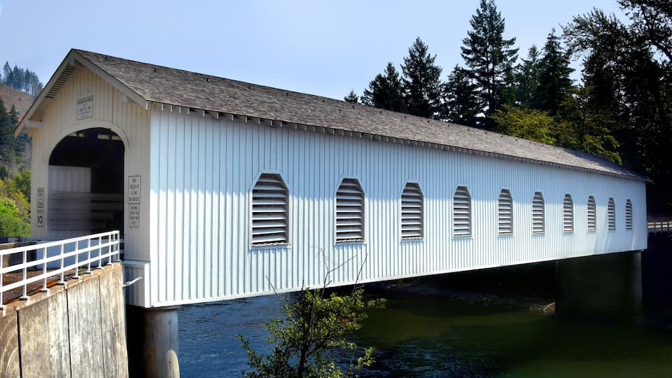 A covered bridge with multiple arched windows and a metal roof.