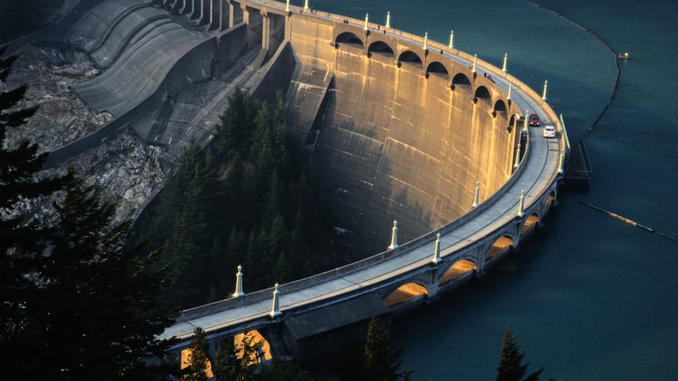 A large dam with a road running alongside it.