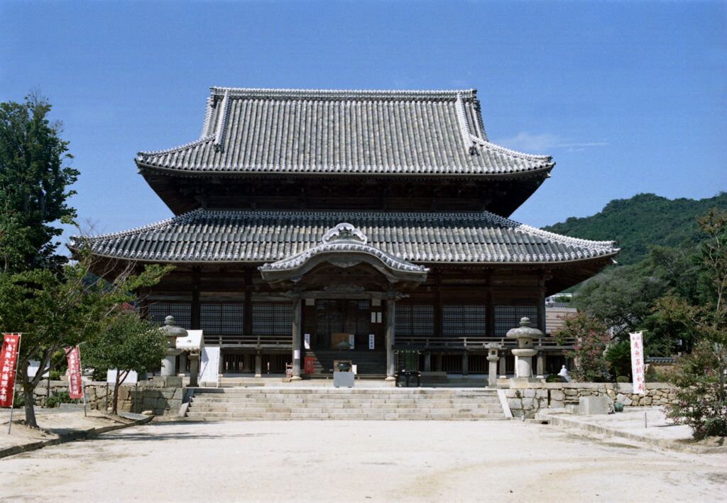 A traditional Japanese building with a tiled roof and a stone staircase leading up to the entrance.